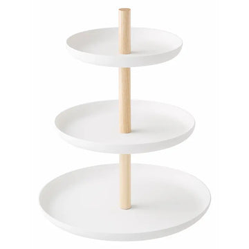 Dreistöckige weisse Etagère mit drei runden Schalen und hellen Holzstangen vor hellem Hintergrund. Sie eignet sich zum Servieren von Desserts und kleinen Leckereien.