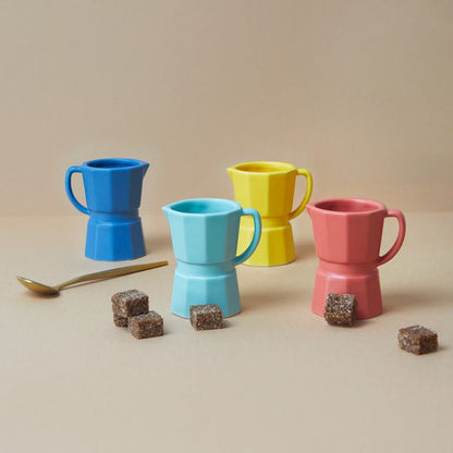MOKA Kaffee-Tassen von Balvi im 4er-Set in Farbmix auf beige Tischfläche, dekoriert mit Löffel und Zuckerwürfeln.
