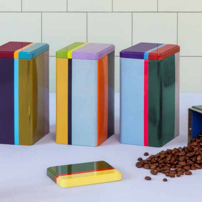 Drei multicolor Weissblech-Vorratsdosen aus dem „Yara“ 4er Set auf der Arbeitsfläche, Deckel liegt vorne; Kaffeebohnen und geöffnete Dose im Hintergrund.
