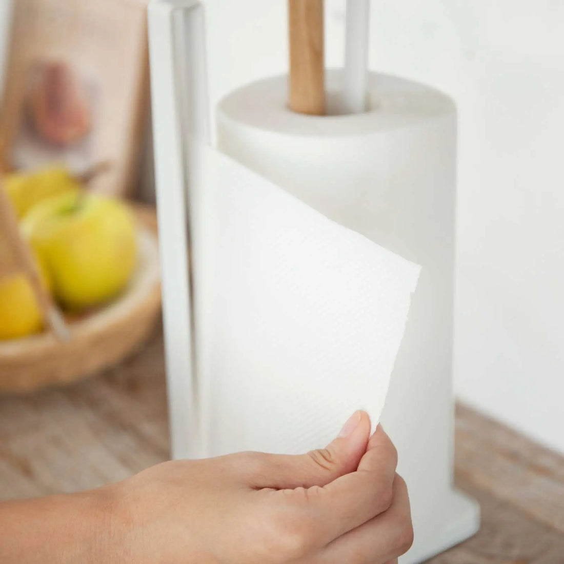 Nahaufnahme: Hand zieht ein Blatt Küchenpapier am TOSCA Halter ab; seitlicher Metallbügel unterstützt kontrolliertes Abreissen.