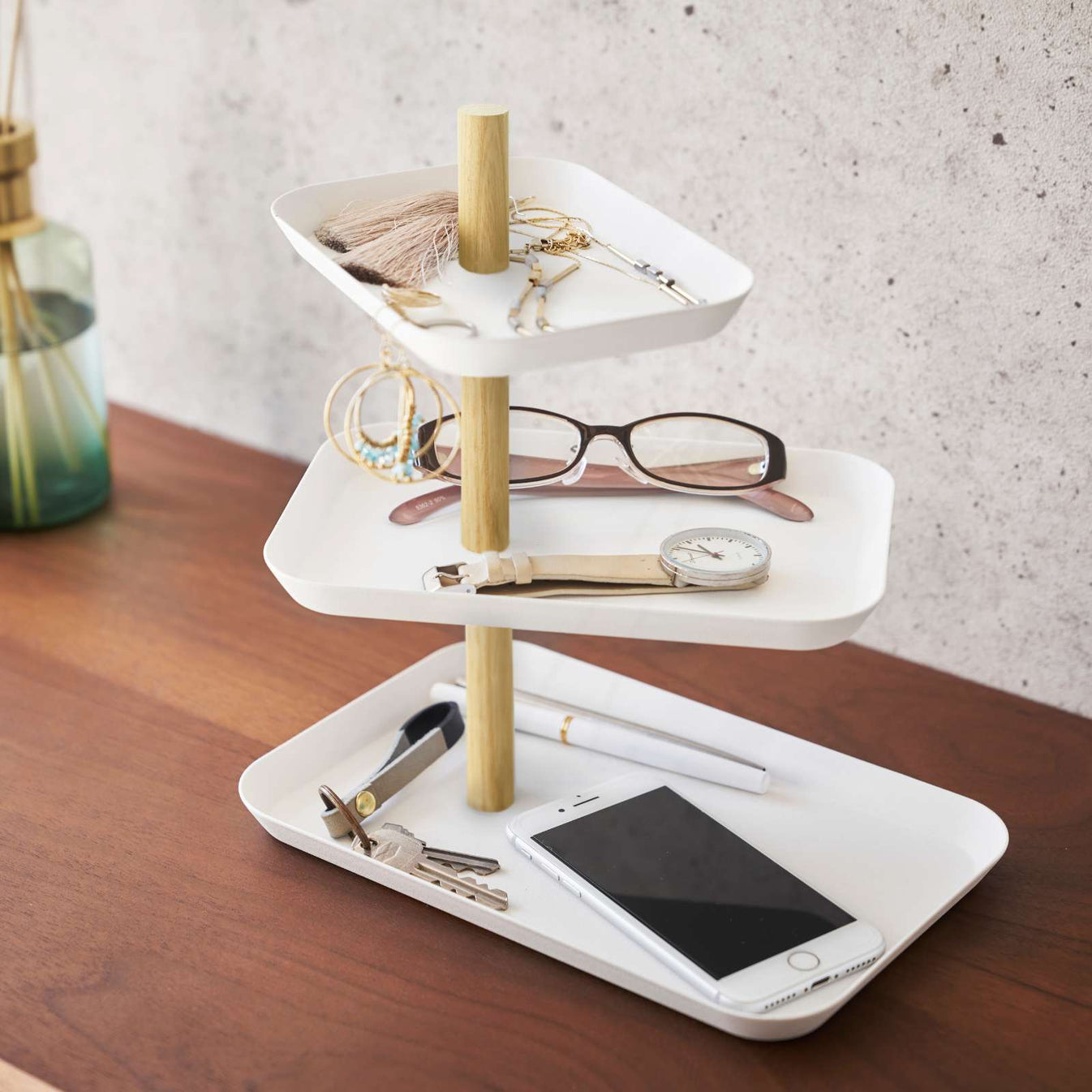 Rechteckige 3-stöckige Étagère in Weiss auf einem Holztisch, dekoriert mit Schmuck, Brille, Uhr, Schlüsseln und Smartphone.