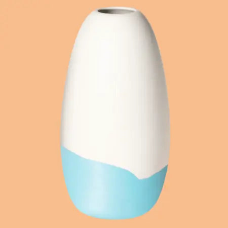 Konische Porzellanvase „Iapetus - hellblau“, seidenmatt weiss glasiert mit hellblauem Akzent am unteren Bereich, freigestellt vor orangem Hintergrund.