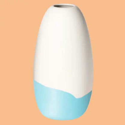 Konische Porzellanvase „Iapetus - hellblau“, seidenmatt weiss glasiert mit hellblauem Akzent am unteren Bereich, freigestellt vor orangem Hintergrund.