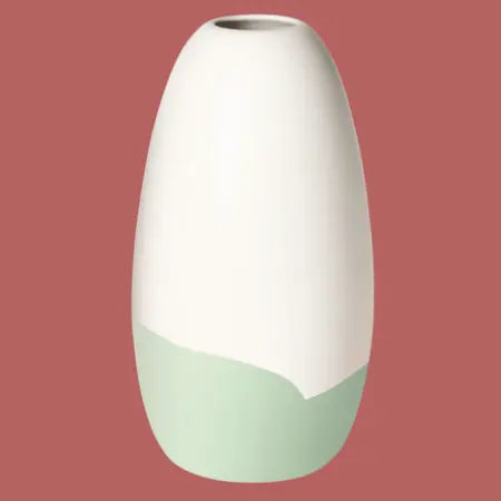 Konische Porzellanvase „Iapetus - hellgrün“, seidenmatt weiss glasiert mit hellgrünem Akzent am unteren Bereich, freigestellt vor rotem Hintergrund.