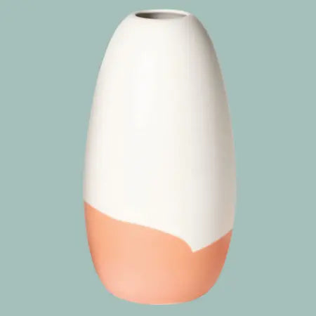 Konische Porzellanvase „Iapetus - orange“, seidenmatt weiss glasiert mit orangem Akzent am unteren Bereich, freigestellt vor pastell hellblauem Hintergrund.