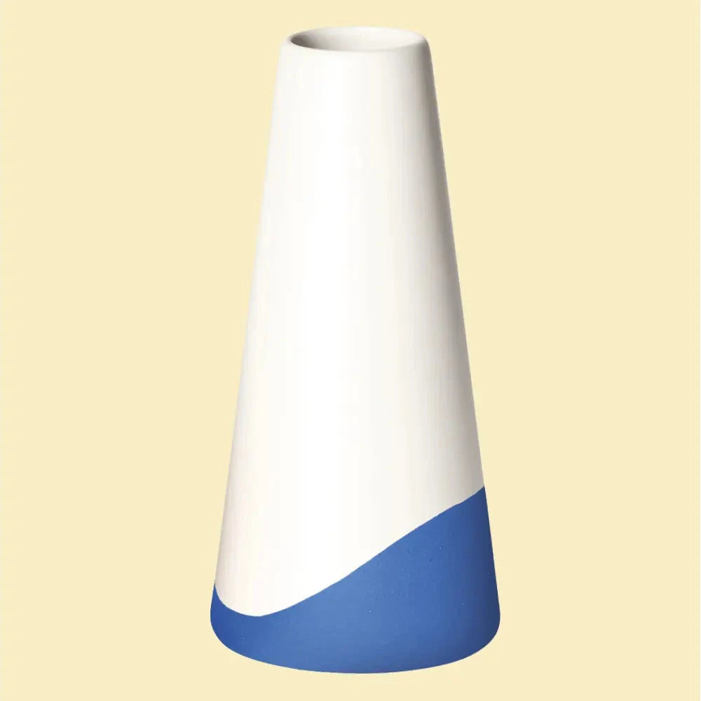 Konische Vase „Neptun“ aus Porzellan, weiss seidenmatt mit blauem Farbakzent am unteren Rand, freigestellt vor hellgelbem Hintergrund.