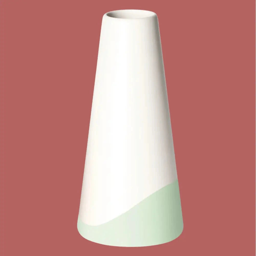 Handgefertigte Porzellanvase „Neptun“ in Weiss mit hellgrünem Farbschwung am Fuss, freigestellt vor rotem Hintergrund.