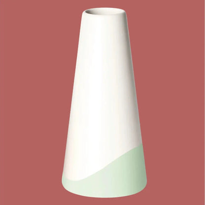Handgefertigte Porzellanvase „Neptun“ in Weiss mit hellgrünem Farbschwung am Fuss, freigestellt vor rotem Hintergrund.