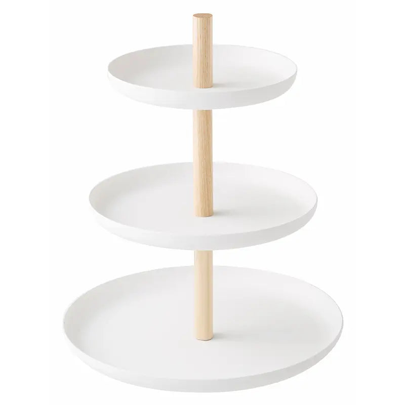 Dreistöckige weisse Etagère mit drei runden Schalen und hellen Holzstangen vor hellem Hintergrund. Sie eignet sich zum Servieren von Desserts und kleinen Leckereien.